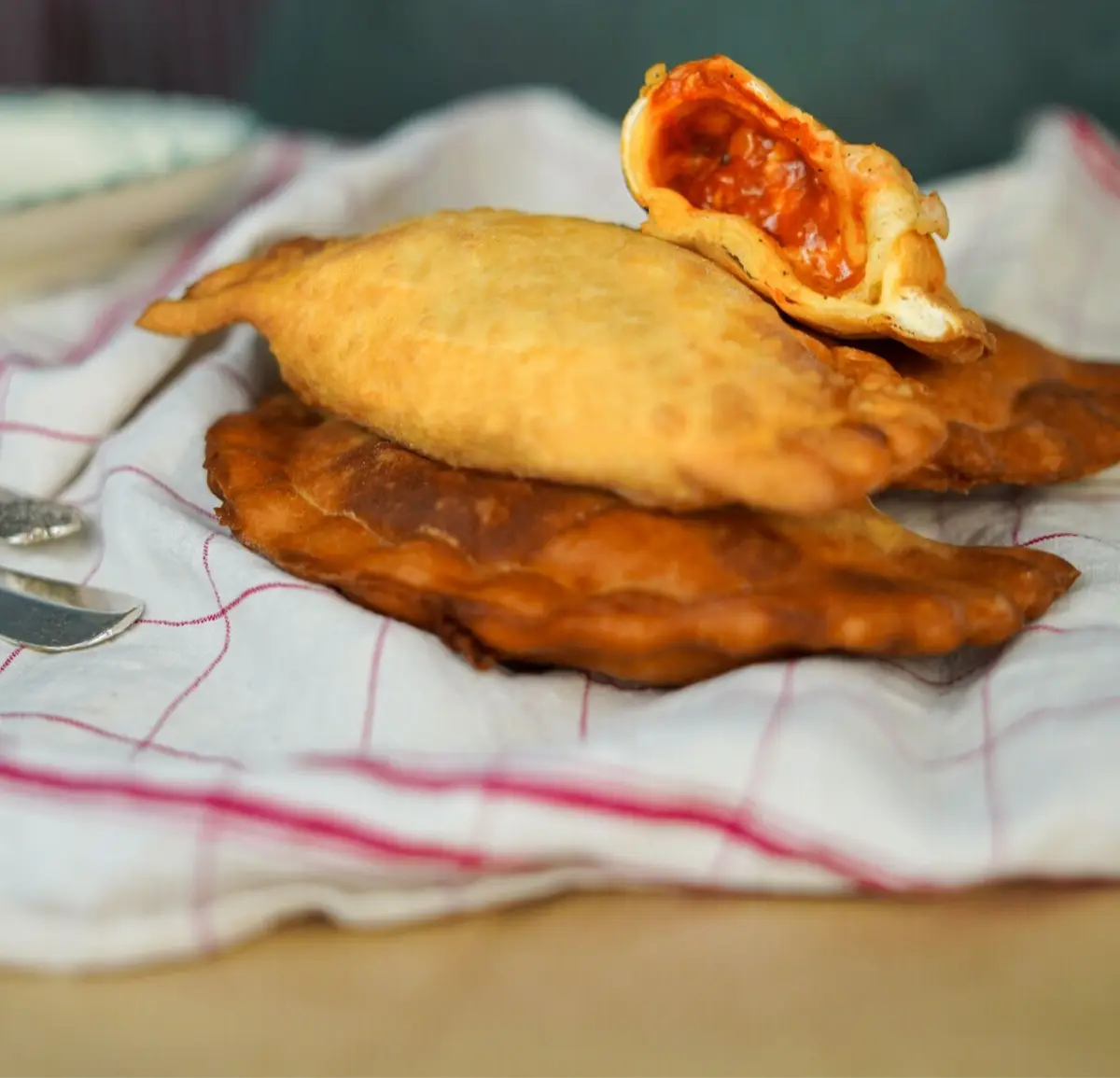 Panzerotti dorés sur un torchon, l'un ouvert sur sa sauce tomate
