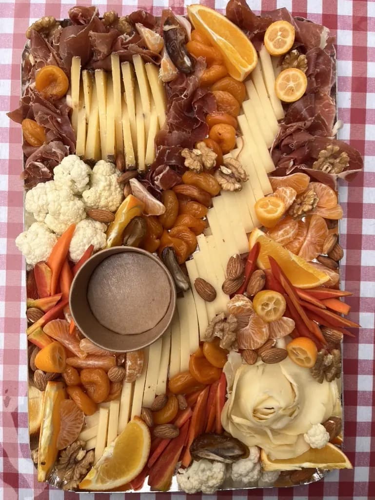 Grande planche apéritif : charcuterie, fromages, agrumes, fruits secs et légumes croquants autour d'une sauce